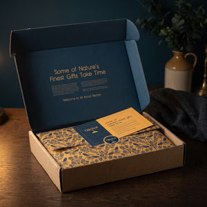 The Signature hamper opened, gold tissue sealed with a story card on top